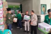 Sejumlah anggota panitia gotong royong menaikkan sejumlah kardus komsumsi ke atas pick up untuk didistribusikan. (foto : istimewa)